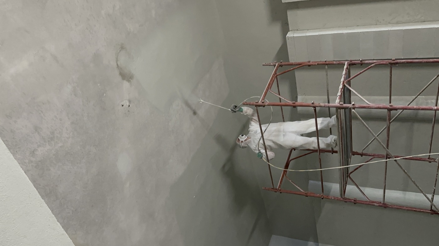Rasatura di una parete su scala prima della tinteggiatura