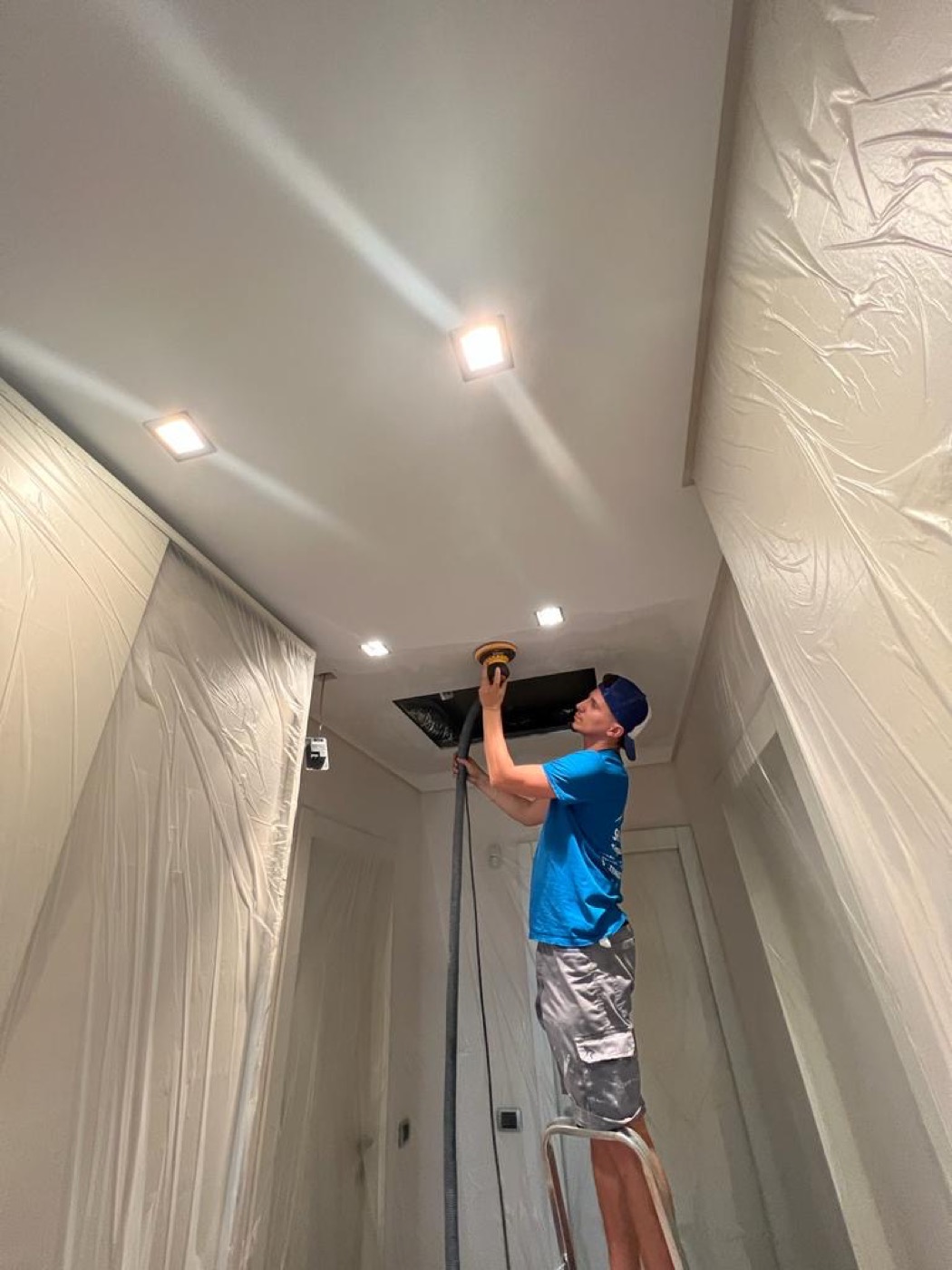 Operaio su ponteggio durante la tinteggiatura di un soffitto