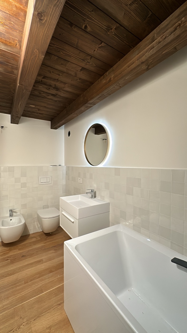 Bagno ristrutturato con mosaico e specchio rotondo
