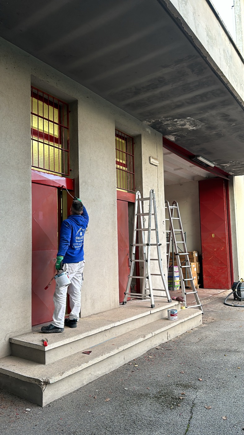 Operaio al lavoro sulla verniciatura di una facciata